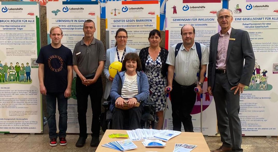 Foto eines sieben-Personen Betreuer*innenteams der Lebenshilfe Mecklenburg-Vorpommern, die vor den aufgebauten Tafeln der Ausstellung stehen.
